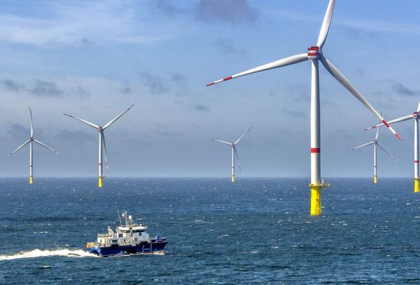 Wind farm in the ocean with a boat in the foreground